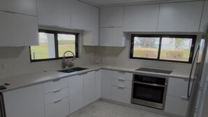 Een keuken met witte kastjes, een spoelbak, een fornuis en een koelkast.