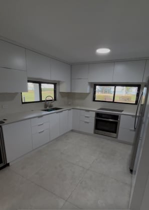 A kitchen with white cabinets, a sink, a stove, and a refrigerator. - Beach Front - Steps to beach 2-bdr remodeled Apt in Río Grande (Río Grande)