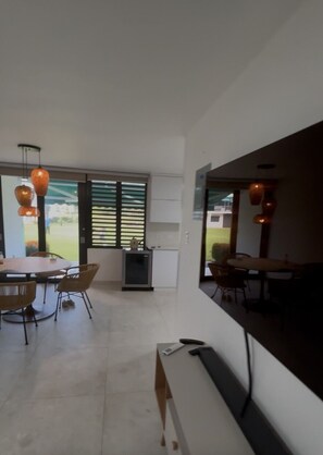 A modern interior with a dining area, a small kitchenette, and a large window with blinds. - Beach Front - Steps to beach 2-bdr remodeled Apt in Río Grande (Río Grande)