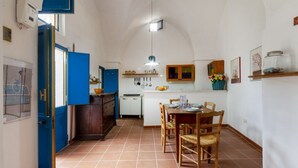 Een kleine keuken met een eethoek, blauwe accenten en een betegelde vloer.