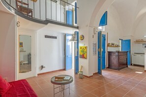 Ein geräumiger Wohnbereich mit einem roten Sofa, einem kleinen runden Tisch und einer Treppe, die zu einer oberen Etage führt.
