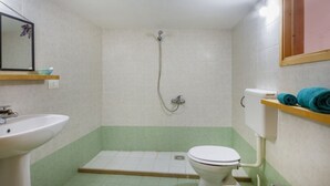 Een badkamer met een wastafel, toilet, douche en spiegel.