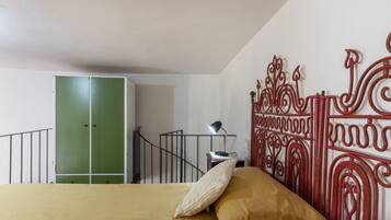 Une chambre à coucher avec un lit, une armoire verte, une rambarde en métal et un élément décoratif mural.