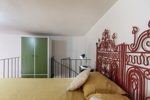 A bedroom with a bed, a green wardrobe, a metal railing, and a decorative wall piece. - This colorful two-level apartment, perfect for two people, is located in Cannole, a quiet village in the heart of Salento, in a courtyard just steps from the town center and the Granafei Castle. It's within easy reach of some of the area's most charming  (Cannole)