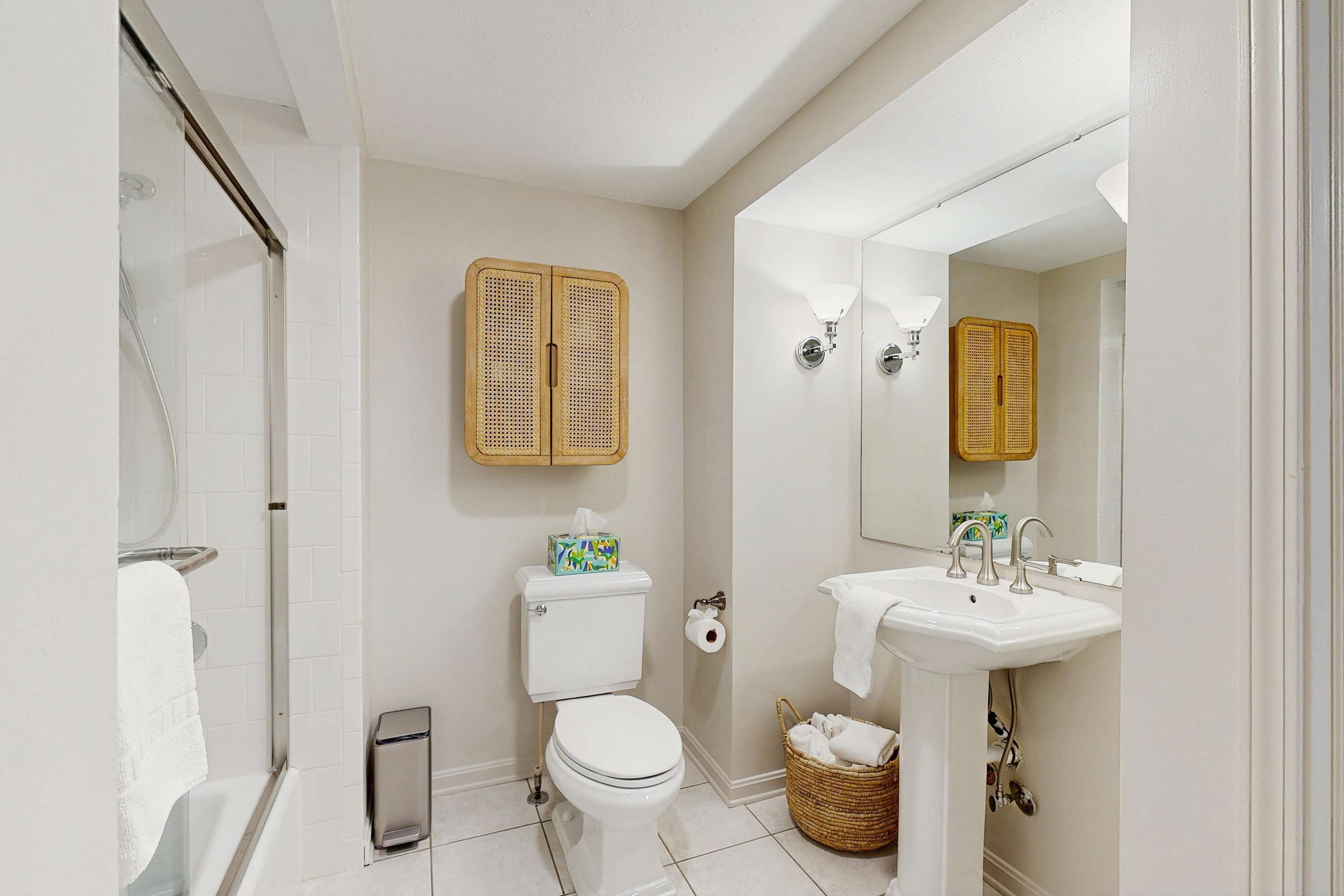 A bathroom with a toilet, sink, shower, and a mirror.