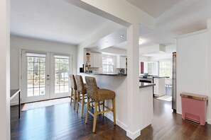 A spacious kitchen with a central island, wooden chairs, and a pink trash bin. - Dartwood Dunes, Dunes, Lakes, Union Pier, Hot Tub (Union Pier)