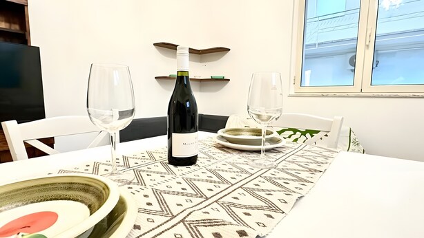 Un tavolo da pranzo con una bottiglia di vino, due bicchieri e un runner decorativo.