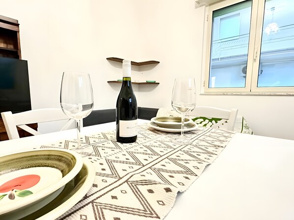 A dining table with a bottle of wine, two glasses, and a patterned table runner.