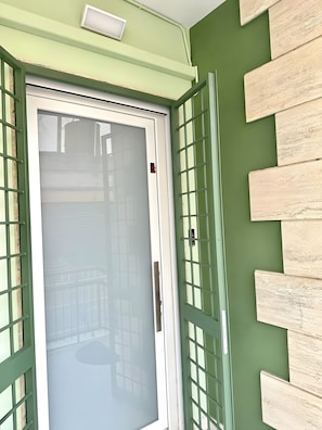 A room with a green wall, a white door with a frosted glass panel, and a green-framed window.