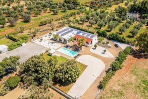 Eine Luftaufnahme eines Anwesens mit Swimmingpool, Solaranlage und angelegtem Garten.