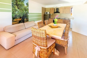 Eine moderne Küche mit Essbereich, inklusive Sofa und Korbstühlen.