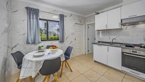 Une cuisine compacte avec des meubles blancs, un four encastré et un coin repas avec une table dressée pour deux personnes.