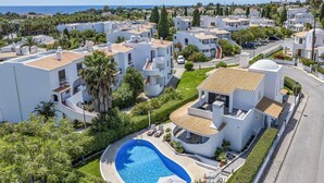 Un quartier résidentiel avec des bâtiments blancs, une piscine et une vue sur la mer.