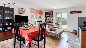 A dining area with a table set for four, a bookshelf, a television, and a window with a view. - Apartment 'La Mansarda - Terrazze Relax A Due' with Balcony, Wi-Fi and Air Conditioning (Cellamare)