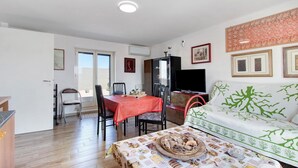 A dining area with a red tablecloth, a sofa with green patterns, and a television on the wall. - Apartment 'La Mansarda - Terrazze Relax A Due' with Balcony, Wi-Fi and Air Conditioning (Cellamare)