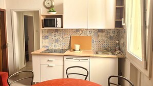 Une petite cuisine équipée d’un four à micro-ondes, d’un évier et d’une horloge murale.