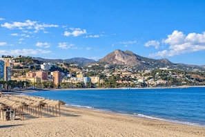 Eine Küstenlandschaft mit Strand, Gebäuden und einem Berg.