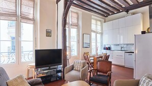 Een woonkamer met een televisie, banken, een eettafel en stoelen.