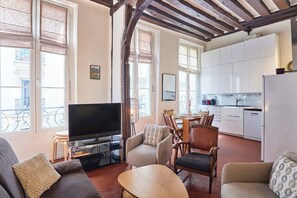 Ein Wohnzimmer mit Fernseher, Sofas, einem Esstisch und Stühlen.