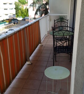 A balcony with a metal railing, a small table, and a chair. - Beautiful apartment with shared pool in Vallauris (Vallauris)