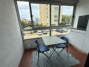 Ein Balkon mit Tisch und Stühlen, Blick auf einen Parkplatz und ein Gebäude im Hintergrund.