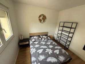 Ein Schlafzimmer mit einem Bett, einer Globus-Dekoration, einem Metallregal und einem Fenster.