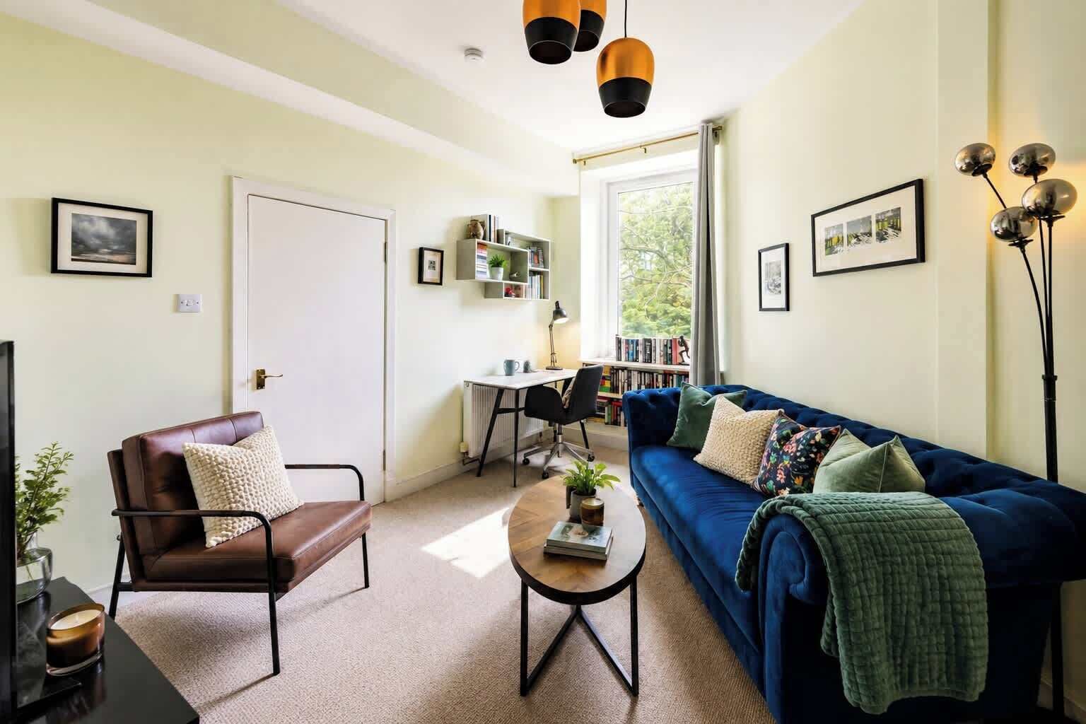 A living room with a sofa, chair, coffee table, bookshelf, and a desk.
