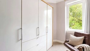 Una habitación con un armario grande, una ventana con vistas a zonas verdes y un sillón de cuero marrón.