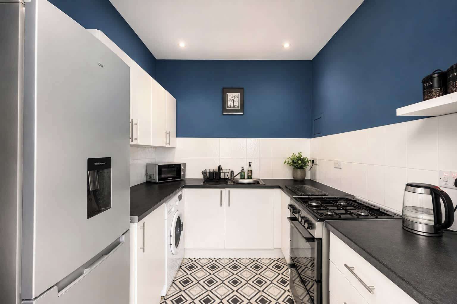 A compact kitchen with a washing machine, microwave, stove, and a coffee maker.