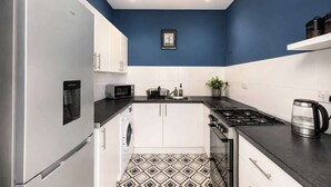 Cocina compacta con lavadora, microondas, estufa y cafetera.