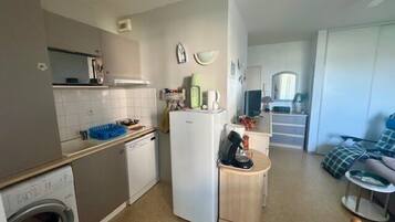 Een kleine keuken met een wasmachine, een koelkast en een spoelbak.