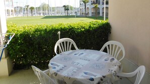 Un balcon avec une table et des chaises, donnant sur une pelouse bien entretenue et un immeuble doté de balcons.