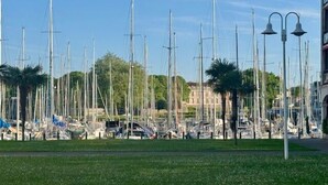 Un port de plaisance où sont amarrés de nombreux voiliers, des lampadaires et un bâtiment en arrière-plan.