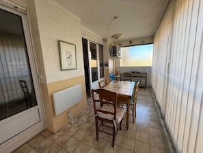 A dining area with a table and chairs, a radiator, a window, and a kitchen area. - Apartment with balcony and parking Cagnes-sur-Mer (Cagnes-sur-Mer)