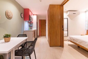 Ein modernes Zimmer mit einem Bett, einem Esstisch mit Stühlen, einer Küchenzeile und einer Holzwand.