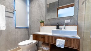 Un baño moderno con inodoro, lavamanos y espejo.