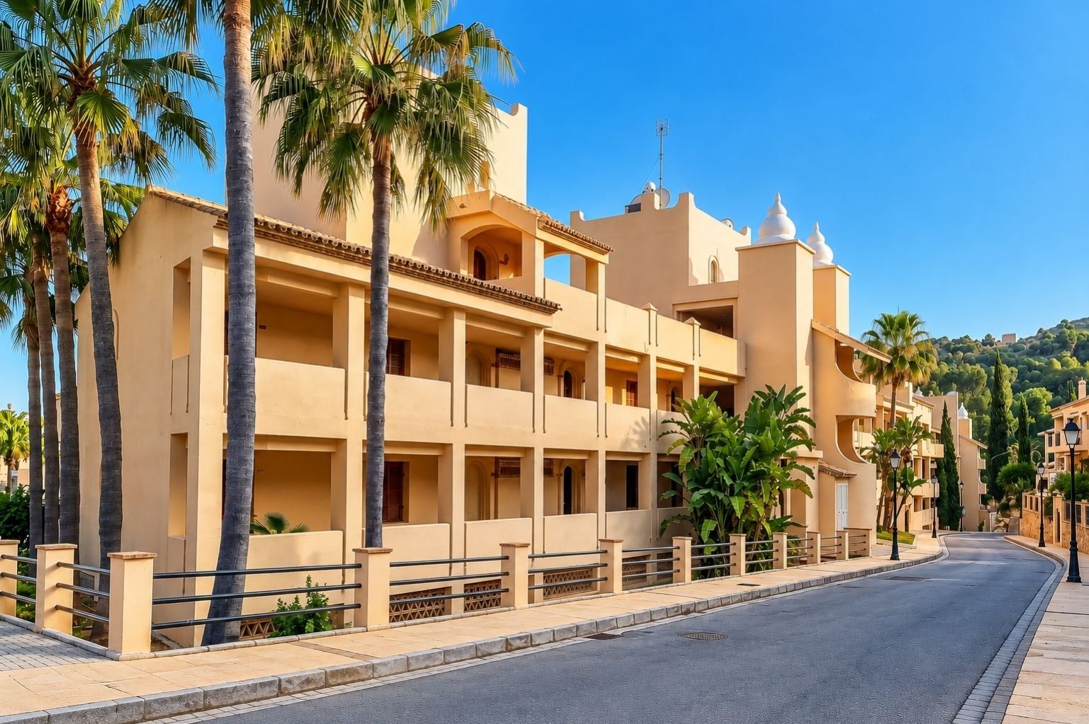 A multi-story hotel with balconies, palm trees, and a clear sky.