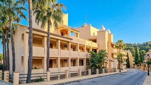 A multi-story hotel with balconies, palm trees, and a clear sky. - GuestReady - Santa Maria Village (Marbella)