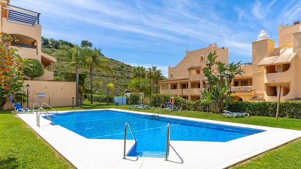 A swimming pool with lounge chairs, a lifebuoy, and a view of hillside buildings. - GuestReady - Santa Maria Village (Marbella)