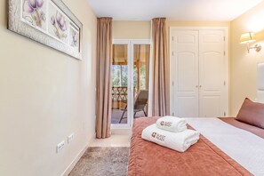 Ein Hotelzimmer mit einem Bett, einem Sessel, einer Tür und Blick nach draußen.
