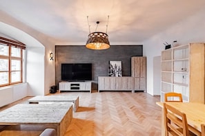 Ein modernes Wohnzimmer mit großem Fernseher, Holzmöbeln und einer außergewöhnlichen Deckenleuchte.