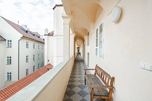 Ein Korridor mit Schachbrettboden, einer Holzbank und weißen Wänden mit Fenstern.