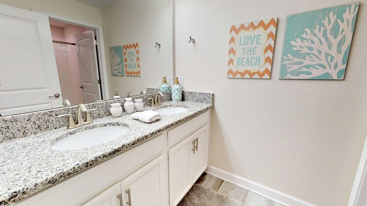 A bathroom with two sinks, a mirror, and decorative wall art.