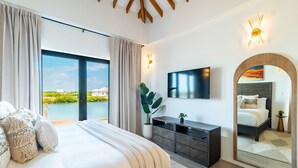 Camera da letto con un letto grande, una TV, un comodino, uno specchio e vista su un corpo d'acqua.