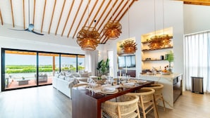 Una cocina moderna con una isla central, suelo de madera y vista a un jardín.