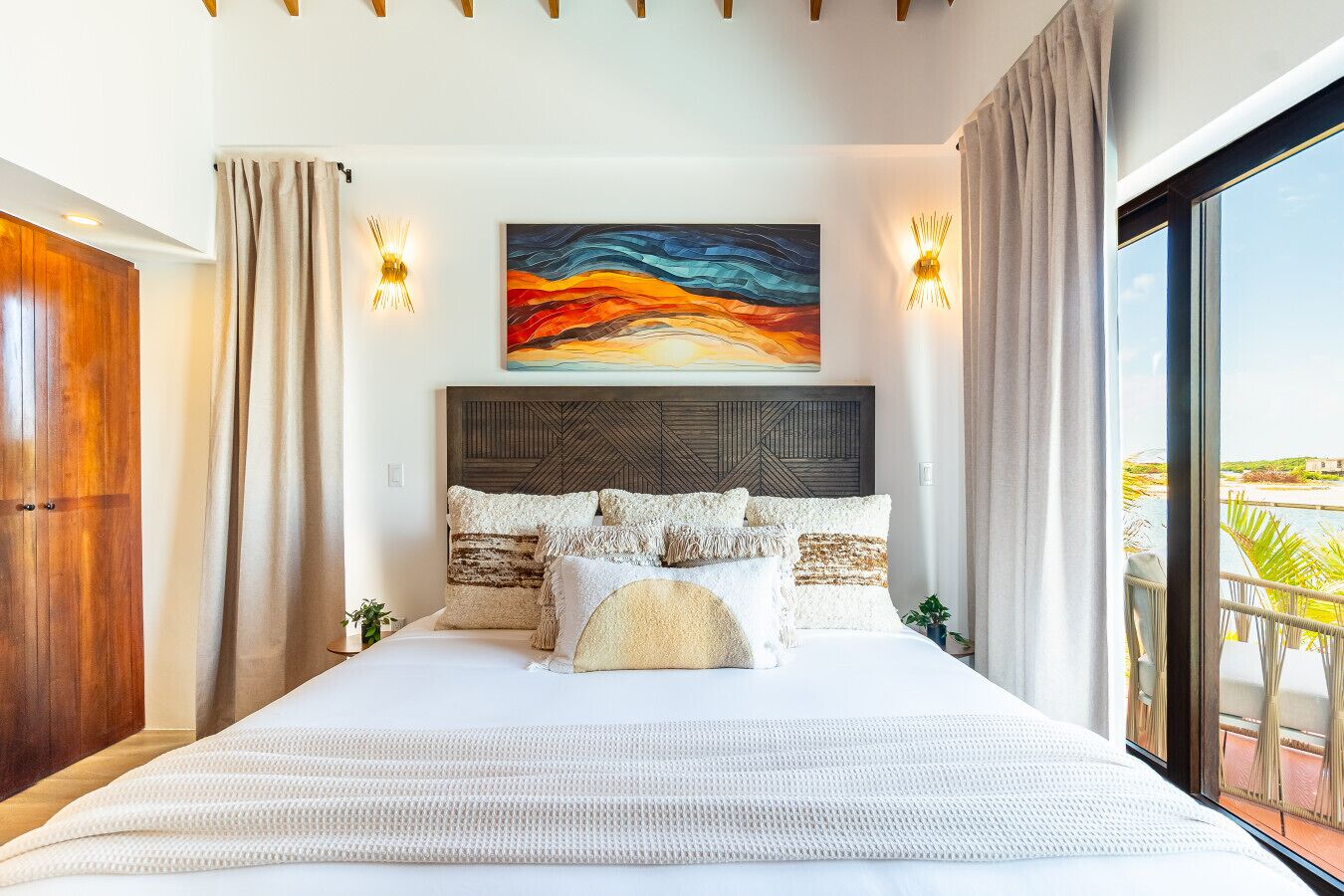 A modern bedroom with a large bed, a geometric headboard, and a colorful abstract painting above it.