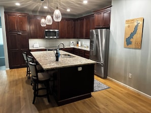A modern kitchen with dark wood cabinets, stainless steel appliances, and a granite countertop.