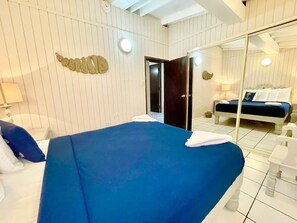 Une chambre d’hôtel comprenant un lit, un miroir, une salle de bain avec une baignoire et une porte donnant sur une autre pièce.