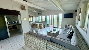 A spacious living area with a large sofa, a dining table, and a kitchen in the background. - Apto 4B Flamenco Beachfront Villas with Ocean View (Flamenco)