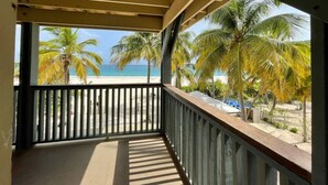A balcony with a view of a beach and palm trees. - Apto 4B Flamenco Beachfront Villas with Ocean View (Flamenco)